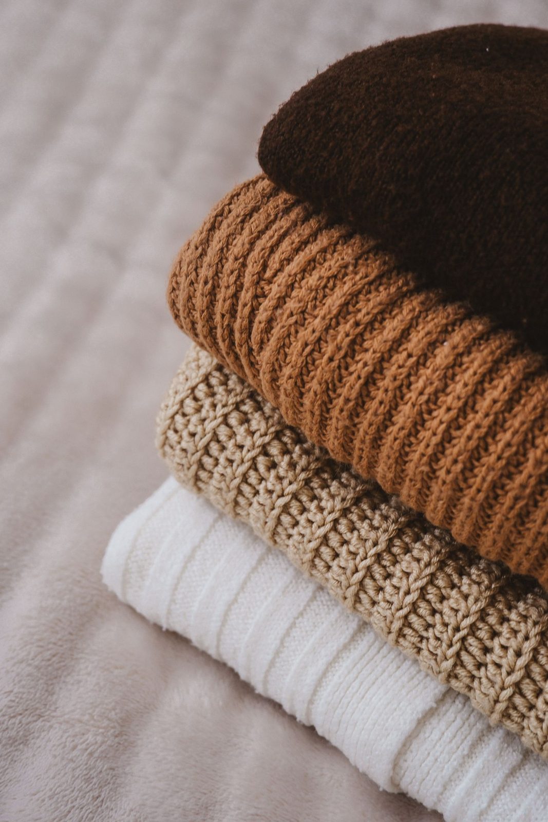 A stack of folded lambswool knitwear in neutral shades